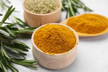 Aromatic curry powder and fresh rosemary on white table, closeup
