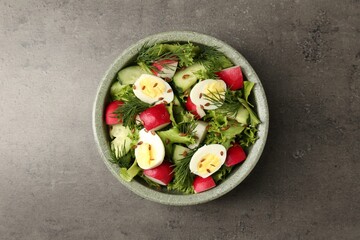 Delicious salad with radish, lettuce and boiled quail eggs on grey table, top view