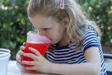 little girl drinking juice from a plastic cup. 
