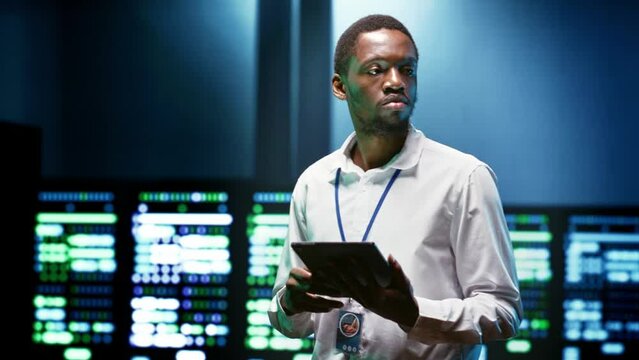 African american specialist using tablet to check data center security features protecting against unauthorized access, data breaches, DDoS attacks and other cybersecurity threats