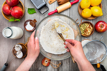 woman kneads the dough with a wooden spoon for a sweet apple pie. View from above.