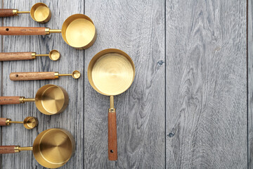 measuring cups with wooden handles on gray kitchen table. View from above. Space for text.