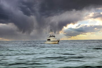 Fishing boat in open waters. Storm clouds over calm sea's with boat heading to shore. Dark grey...