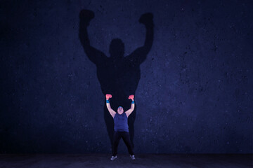 Overweight man with boxing glove raising hands after exercise