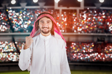 Arabic football concept - Arabian man standing with blurred soccer stadium background