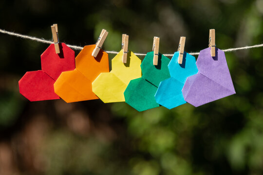 origamis de cora&ccedil;&otilde;es com as cores do arco-&iacute;ris pendurados em um varal de barbante, simbolizando o amor e contra a homofobia e apoiando a causa LGBtQIAP+