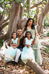 Fototapeta premium beautiful indian family sisters smiling with a bindi and traditional sari dress and kurta sitting on a tree