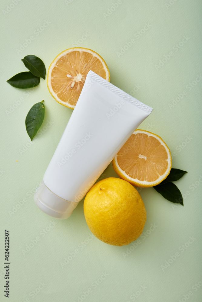 Sticker A white plastic tube for beauty cosmetics, mockup for face creams and cleansers with lemon extract ingredients. Advertising photo for natural organic cosmetics. Lemon and leaves on pastel background.