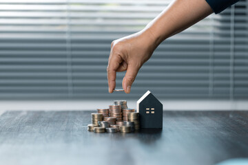 Saving money for house and real estate. Woman hand protecting on stack coins and house model on...