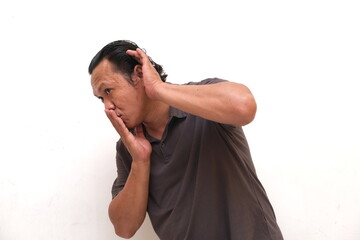 pose of an asian man listening or eavesdropping. The expression of an Indonesian man is...