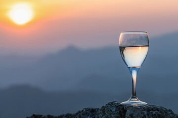 Glass of white wine and view to beautiful mountains sunset background.