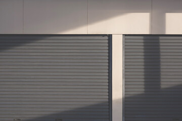 Light and shadow on surface of the old 2 steel roller Shutter Doors with gypsum board wall of Warehouse building, front view with copy space