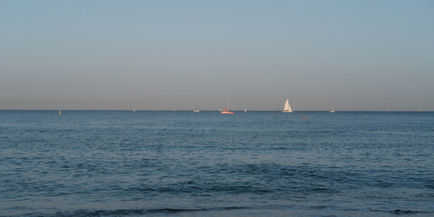 Calm seascape of the Mediterranean coast with yachts in the background and a flat horizon. The...