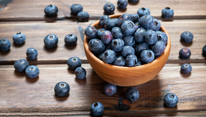Freshly picked blueberries in a wooden bowl on a wooden background. Healthy food and nutrition.