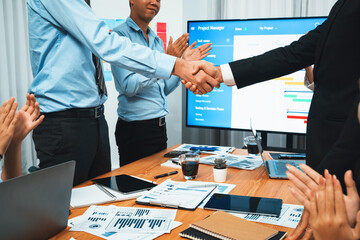 Cheerful meeting room, businesspeople celebrate with handshaking. Successful project was completed...