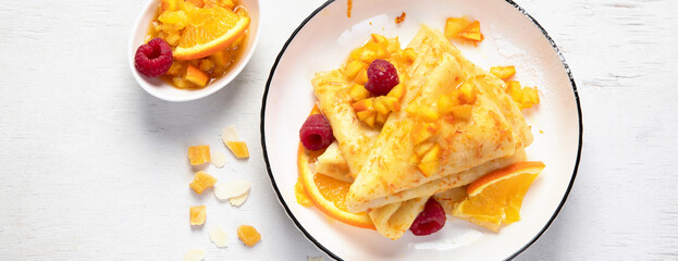 Crepe suzette with orange sauce and raspberry for a delicious breakfast.
