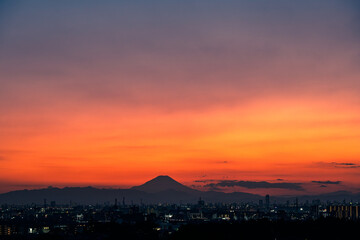 茜色の夕空を背にして臨む富士山と街の灯