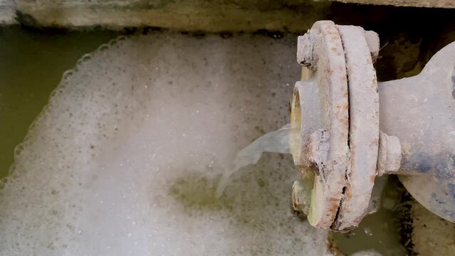 Dirty waste water coming out from pipe. Pouring water produce foam on the pond. Chemical waste water from industrial process. Wastewater Treatment Procedure (WWTP)