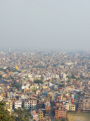 Fototapeta na wymiar View of the Kathmandu city from the top of the Syambhunath temple, showing the congested buildings with some trees. Kathmandu city