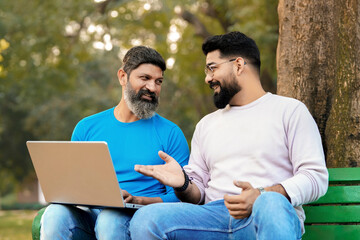 Two indian male discuss and using laptop at park