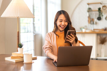 Young smiling asian woman relax using laptop conference work,learning education,study online,webinar podcast,creative woman looking at screen typing message with smartphone at home