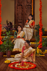 Women decorating floor with flowers on the occasion of Onam