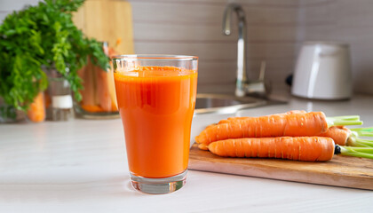 Glass of fresh squeezed carrot juice on the table of the kitchen. Healthy eating, detox, dieting...