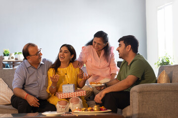 Happy Indian family sitting together at home and talking to each other on Raksha Bandhan
