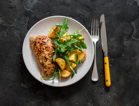 Mustard, greek yogurt marinade roasted turkey  and new potatoes, arugula salad on a dark background, top view