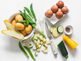 Ingredients for making frittata - potatoes, zucchini, eggs on a light background, top view