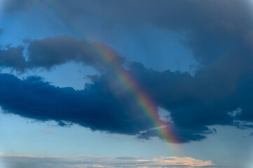 Fototapeta premium Amazing bright rainbow in a beautiful blue cloudy sky after rain and thunder