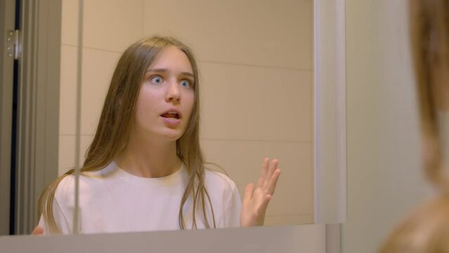 Young woman ranting in the mirror, in Slow Motion. A frustrated person looking in the bathroom mirror.