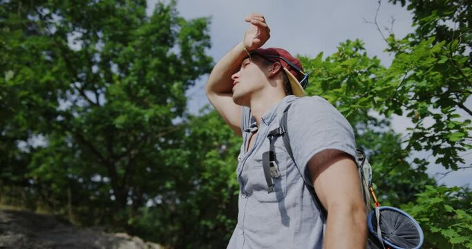 man looking into the sun, sunny athletic young guy, snapback hat, summer vibes, hiking in the forest, trail walking