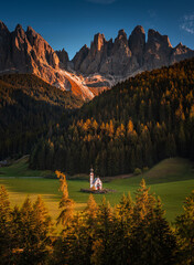 Val Di Funes, Dolomites, Italy - The beautiful St. Johann in Ranui Church at South Tyrol with the Italian Dolomites and blue sky at background with warm autumn sunset lights
