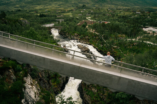 Man standing on the bridge over the V&oslash;ringsfossen Waterfall in Norway