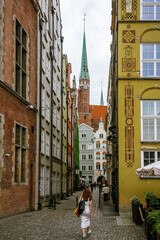 Woman walking up a lane in the old town of Gdańsk, Poland - obrazy, fototapety, plakaty