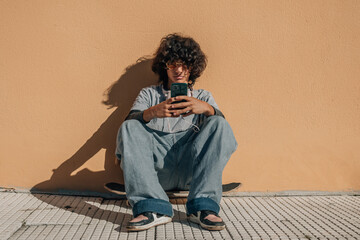 teenager boy with skateboard and mobile phone on the wall © tetxu