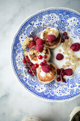 Obraz premium vintage plate with cottage cheese pancakes and berries. syrniki with greek yogurt, raspberries and currants. 
