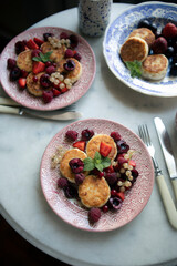 syrniki with seasonal berries top view. breakfast with cottage cheese pancakes on a vintage plate. breakfast for two on a marble table.	