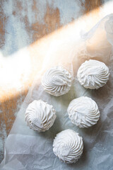 white zephyr closeup top view. vanilla marshmallow on crumpled parchment paper. marshmallows with sun glare.	