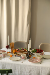 table setting with white tablecloth. snacks and candles on a decorated indoors table. table waiting for guests	