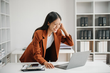 Asian business woman are delighted and happy with the work they do on their tablet, laptop and taking notes at the office..