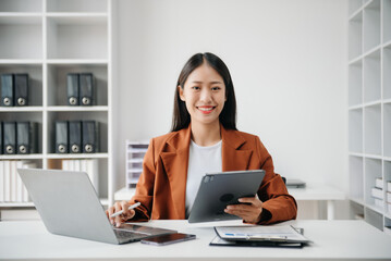 Business woman using tablet and laptop for doing math finance on an office desk, tax, report, accounting, statistics, and analytical research concept in office