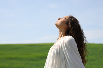 Single woman breathing fresh air in a green field