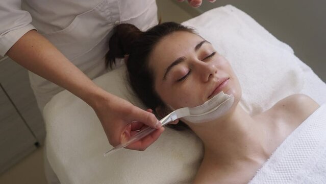 Young beautiful woman receiving facial mask in spa beauty salon - indoors. Spa and wellness. Skin care concept. Close up