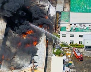 Aerial view of Fire in industrial building. Multi-storey concrete hangar with flames. Factory emergency concept.