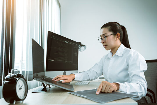 Woman asian software developers are analyzing together about the code written into the program on the computer in office room.