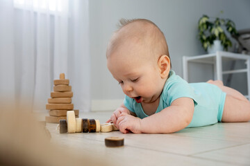 Infant play wooden toys on floor at home. Child development with non plastic wooden toys. Eco friendly childhood. Cute little baby.