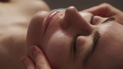 Close-up view of a woman receiving a facial massage at an aesthetic salon. Cosmetology concept. Skin care, spa concept, treatment, facial massage. - Powered by Adobe