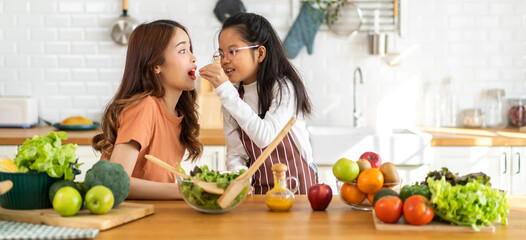 Portrait of enjoy happy love asian family mother and little asian girl daughter child having fun help cooking food healthy eat together with fresh vegetable salad and ingredient in kitchen